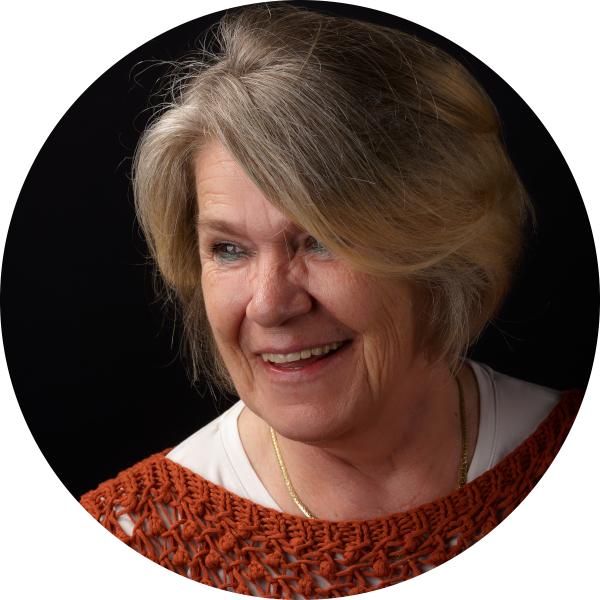 Porträt von Heike Hollenhorst mit rotem Oberteil vor dunklem Hintergrund.